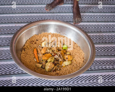 Les pieds des femmes et de la nourriture typique d'attente pour les sénégalais de la famille à manger ensemble à la manière traditionnelle. Le nom est 'Thiéboudieune'. Le Sénégal. Un Banque D'Images