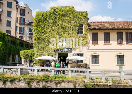 Milan, Italie : pizzeria italienne dans bâtiment ancien, avec la façade couverte de jasmin grimpant, donnant sur la voie navigable Naviglio Grande Banque D'Images