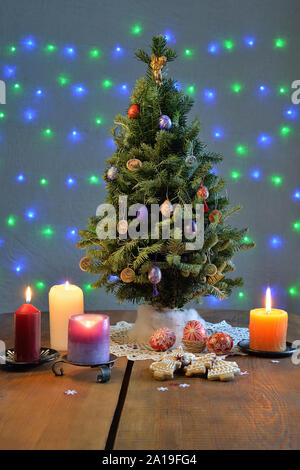 Arbre de Noël entouré par les bougies, les cookies et les oeufs colorés sur la table. Banque D'Images