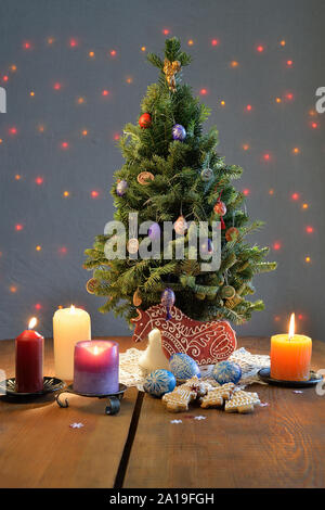 Arbre de Noël entouré par les bougies, les cookies et les oeufs sur la table Banque D'Images