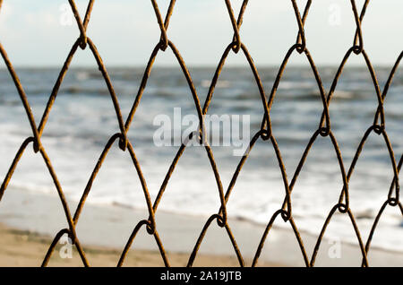 Clôture en fil mesh sur l'arrière-plan de la plage et de la mer Banque D'Images