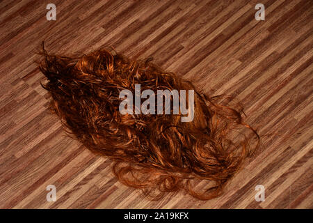 De longs cheveux rouges sur le sol dans un salon de coiffure, cheveux coupé rouge dans un salon de beauté. Banque D'Images