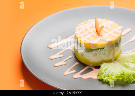 Péruvien traditionnel plat appelé causa faite de purée de piment (AJI) et le jus de lime et remplie de légumes (maïs, pois, carottes) et Banque D'Images