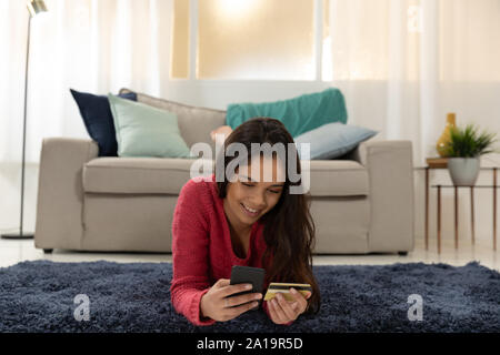 Jeune femme à la maison en utilisant un smartphone Banque D'Images