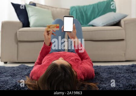 Jeune femme à la maison en utilisant un smartphone Banque D'Images