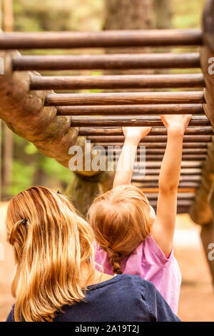 Mère Fille d'appui dans l'aire de jeux avec de l'escalade et accroché sur une échelle. Banque D'Images