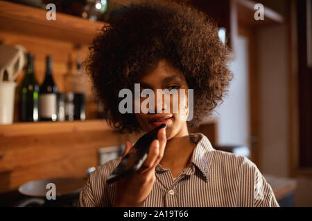 Young woman using smartphone in kitchen Banque D'Images