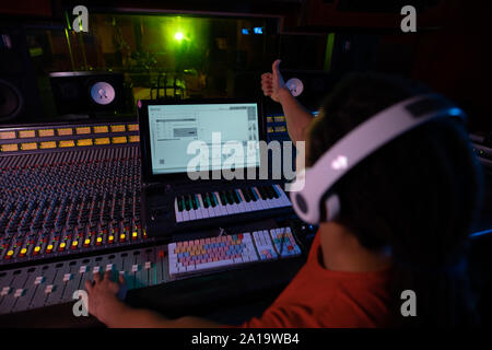 Le producteur de musique d'hommes travaillant à la table de mixage dans un studio de son Banque D'Images