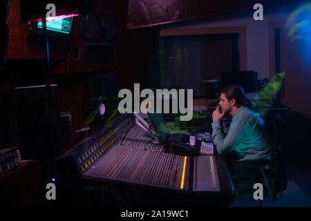 Le producteur de musique d'hommes travaillant à la table de mixage dans un studio de son Banque D'Images
