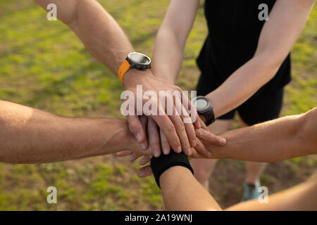 Les jeunes adultes stacking hands at an outdoor fitness bootcamp Banque D'Images