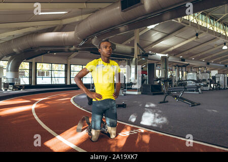 Mobilité African American male à genoux avec les mains sur la hanche dans le centre de remise en forme Banque D'Images