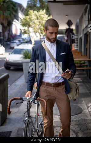 Young man using smartphone et la tenue d'un vélo Banque D'Images