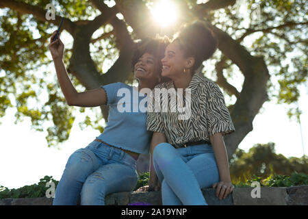 Deux jeunes femmes en tenant l'extérieur selfies Banque D'Images