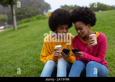 Deux jeunes femmes à l'aide de l'extérieur les smartphones Banque D'Images