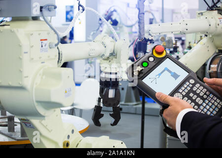 Ingénieur avec télécommande d'appareil. Robot de programmation avec bras robotique. Smart factory Banque D'Images