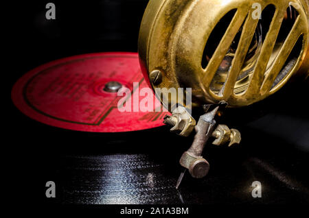 Aiguille et une tête d'un vieux gramophone rare antique faite de métal jaune sur un disque vinyle avec une étiquette rouge close-up Banque D'Images