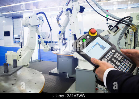 Ingénieur avec télécommande d'appareil. Robot de programmation avec bras robotique. Smart factory Banque D'Images