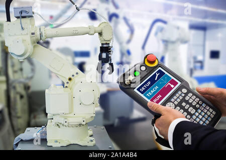 Ingénieur avec télécommande d'appareil. Robot de programmation avec bras robotique. Smart factory Banque D'Images