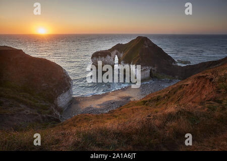 Lever du soleil à l'alcool au dinosaure hautes cheminées arch, Flamborough Head, East Yorkshire, UK Banque D'Images