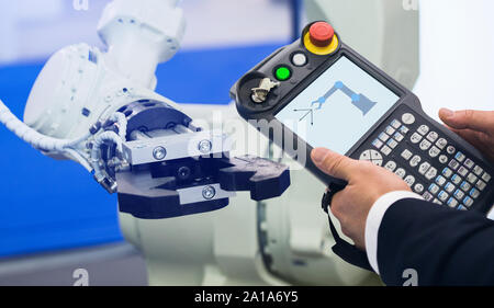 Ingénieur avec télécommande d'appareil. Robot de programmation avec bras robotique. Smart factory Banque D'Images