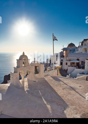 Vue pittoresque de beffroi avec cloches suspendues drapeau grec et à l'église sur la mer bleue en arrière-plan Oia Santorini Grèce sur sunny day Banque D'Images