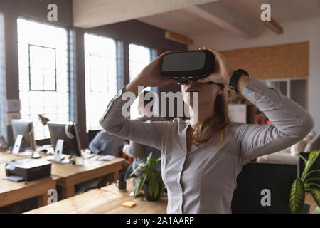 Jeune femme professionnelle créative à l'aide de casque VR dans un bureau Banque D'Images