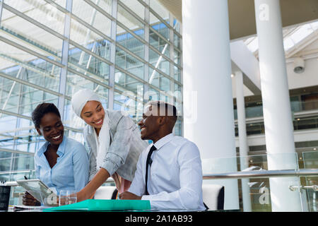 Heureux hommes et les femmes cadres discussing over digital tablet at desk Banque D'Images