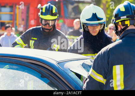 Les pompiers, pompier, couper un verre de voiture et porte en accident de voiture Banque D'Images