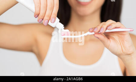 Méconnaissable Woman Putting dentifrice sur une brosse à dents, fond blanc, Panorama Banque D'Images