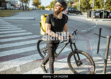 Portrait d'un homme marchant avec messagerie location sur la ville steet, la livraison de nourriture avec sac à dos thermique jaune. Concept de fourniture de produits alimentaires Banque D'Images