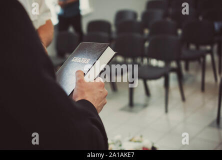 Le pasteur baptiste en Ukraine est titulaire d'une Bible noire. Le prêtre a les mains sur la Bible. Arrière-plan flou et l'espace pour le texte. Banque D'Images