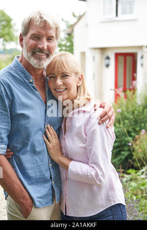 Portrait Of Mature Couple debout dans un jardin en face de maison de rêve en campagne Banque D'Images
