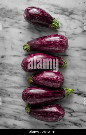 Bébé à rayures aubergines sur surface en marbre disposés dans une rangée. Vue d'en haut, l'image verticale Banque D'Images