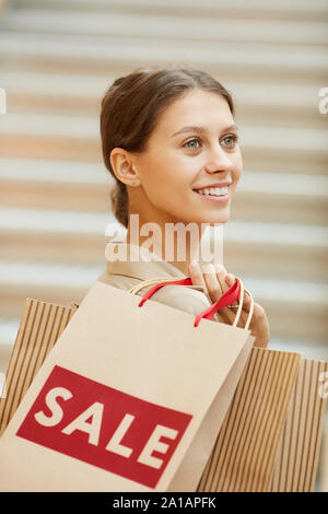 Close-up of happy services à la holding shopping bags elle satisfait ses achats lors de la vente dans le magasin Banque D'Images