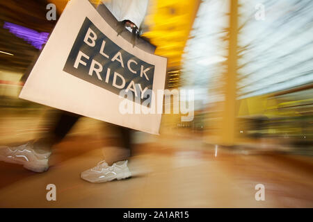 Blurred motion d'accro du holding big sac de papier et marcher le long du centre commercial après le magasinage Banque D'Images