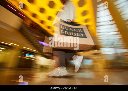 Blurred motion d'accro transportant des sacs de shooping en se promenant dans la galerie marchande après vente Banque D'Images