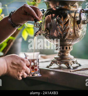 L'homme n'est verser de l'eau à partir de vieux métal traditionnel samovar russe. L'heure du thé. Banque D'Images