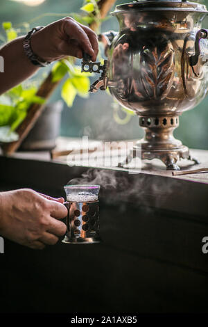 L'homme n'est verser de l'eau à partir de vieux métal traditionnel samovar russe. L'heure du thé. Banque D'Images