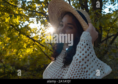 Femme au chapeau de paille et une tenue romantique de détente en plein air à l'automne ou l'été park et bénéficiant de bonnes conditions météorologiques et le coucher du soleil. La belle nature Banque D'Images
