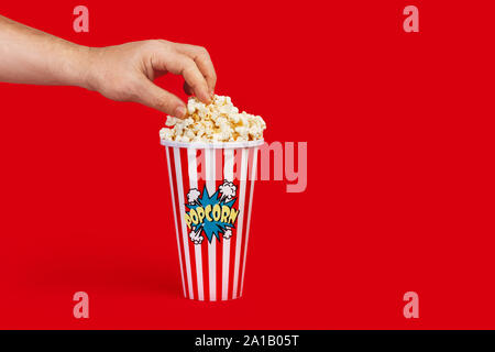 Un homme prenant à partir d'un pop-corn seaux sur fond rouge Banque D'Images