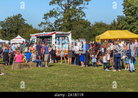 Les adultes et les enfants forment une longue file d'attente à une glace van au cours de l'Épouvantail Belbroughton Festival. Banque D'Images