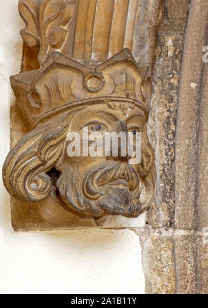 Une tête de pierre à la base de l'arc entrant dans la nef sud de la véranda de l'église paroissiale de St Mary à Worstead, Norfolk, Angleterre, Royaume-Uni, Europe. Banque D'Images