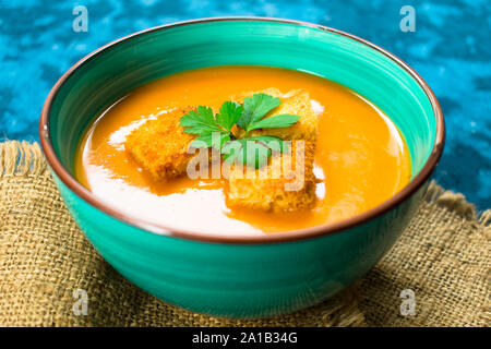 Soupe de purée de potiron et de petits croûtons sur un fond bleu. Close-up. Concept de l'automne menu. Banque D'Images
