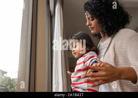 Mère et fille adorable à travers une fenêtre à la maison Banque D'Images