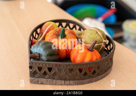 Différentes variétés de citrouilles artificiel décoratif dans un bol en bois en osier sur un compteur de l'agriculteur. Festival de la récolte de légumes d'automne, maison de vacances Hallow Banque D'Images