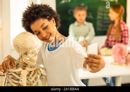 Heureux gosse international aux cheveux bouclés parler photo selfies Banque D'Images