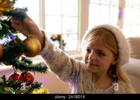 Girl decorating tree à l'époque de Noël Banque D'Images