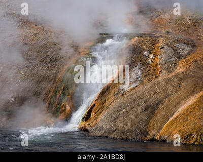 L'eau bouillante jaillit de rochers incrustés de minéraux dans la rivière Firehole, Midway Geyser Basin, Parc National de Yellowstone, Wyoming, USA Banque D'Images