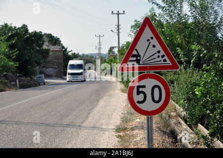 Signe de la limite de vitesse en pleine campagne sur une soirée d'été. La limite de vitesse est de 50 km/h sur une route de gravier. L'accent est mis sur le signe de la limite de vitesse sur la droite. Banque D'Images