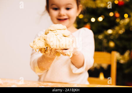 Girl holding dough in front of Christmas Tree Banque D'Images